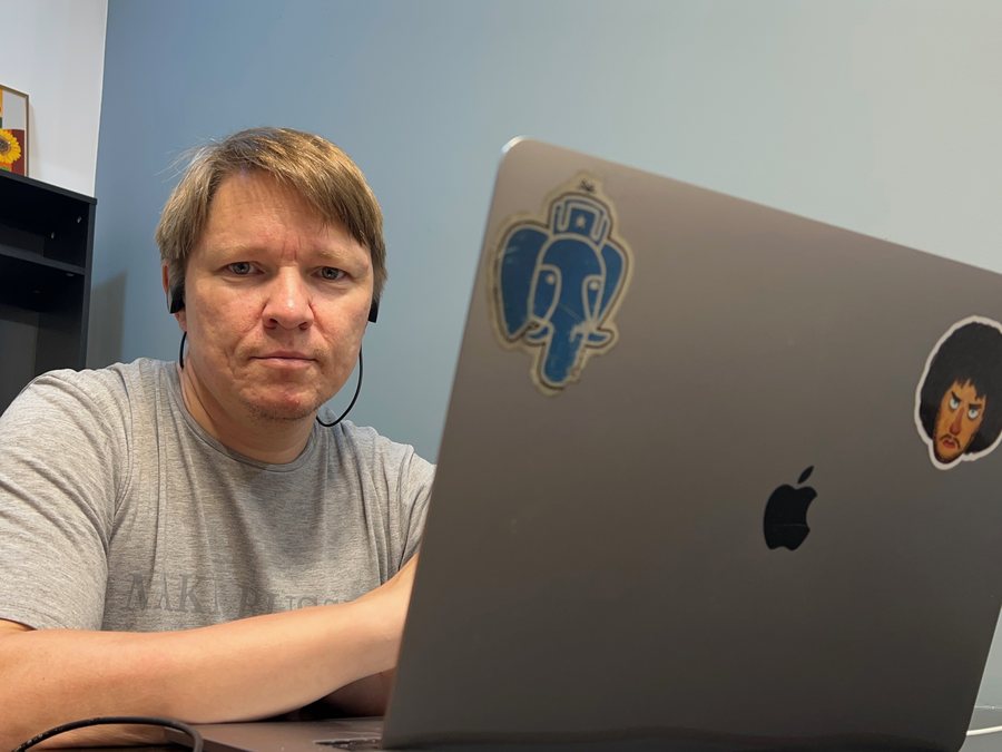 Andrei Lepikhov at his laptop, a PostgreSQL elephant sticker on the lid